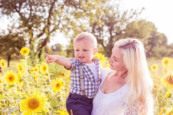Родина ходить по літньому квітковому полю. Щаслива мати і маленький син на сонці. Літо. Соняшники . — стокове фото