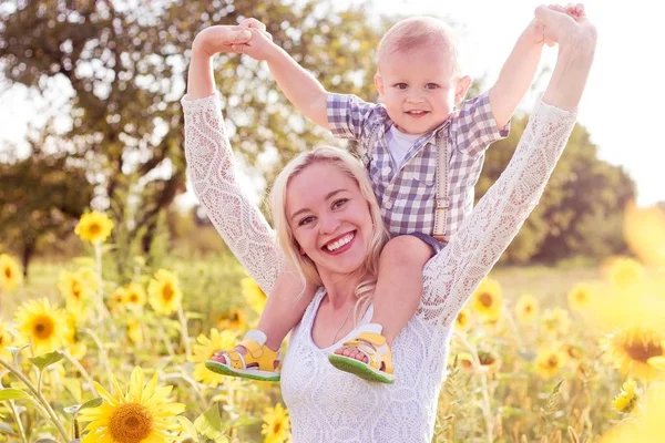 Family is walking along the summer flowering field. Happy mother and little son in the sun. Summer. Sunflowers. — Stock Photo, Image