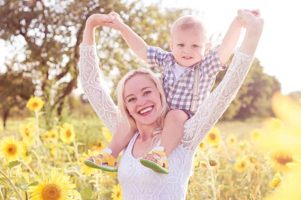 Family is walking along the summer flowering field. Happy mother and little son in the sun. Summer. Sunflowers. — Stock Photo, Image