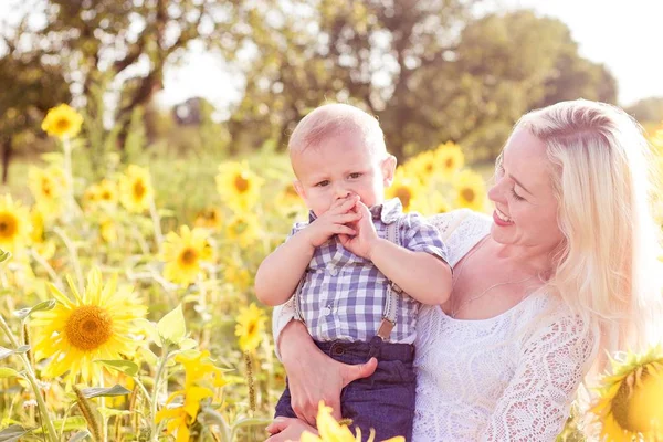 Family is walking along the summer flowering field. Happy mother and little son in the sun. Summer. Sunflowers. — Stock Photo, Image