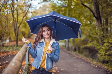 Güzel genç bir kadın onun elinde bir umberella ile sonbahar park boyunca yürüyor. Mutlu kadın sonbahar portresi. A