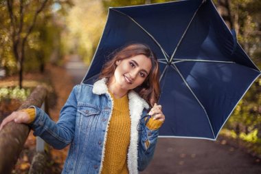 Güzel genç bir kadın onun elinde bir umberella ile sonbahar park boyunca yürüyor. Mutlu kadın sonbahar portresi. A