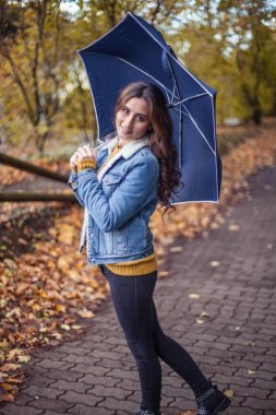 Güzel genç bir kadın onun elinde bir umberella ile sonbahar park boyunca yürüyor. Mutlu kadın sonbahar portresi. A