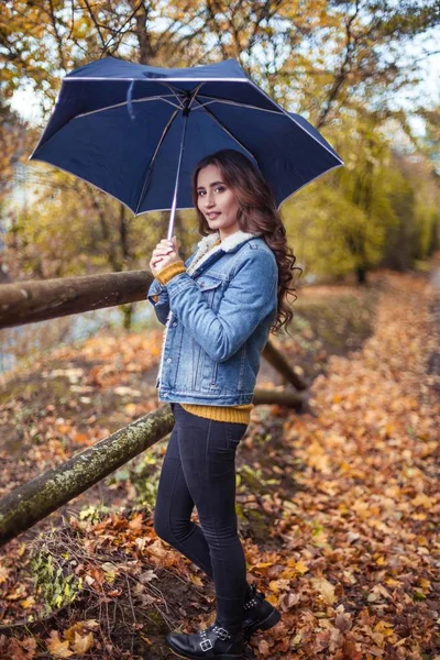 Młoda kobieta piękną jest spaceru wzdłuż parku jesień z umberella w jej ręce. Jesienny Portret młodej kobiety szczęśliwy. A — Zdjęcie stockowe