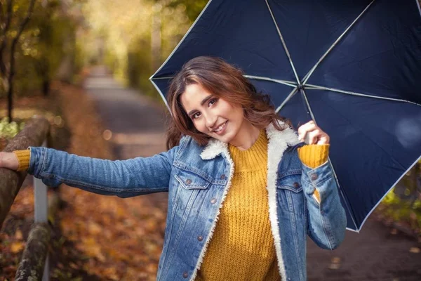 Młoda kobieta piękną jest spaceru wzdłuż parku jesień z umberella w jej ręce. Jesienny Portret młodej kobiety szczęśliwy. A — Zdjęcie stockowe