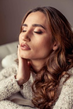 Güzel bir genç kadın rahat bir portresi. Güzel Türk kızı. Sıcak sonbahar. Rahat ev akşam. Genç bir kadın kendini bir battaniyeye sarılmış ve kanepede oturuyor.