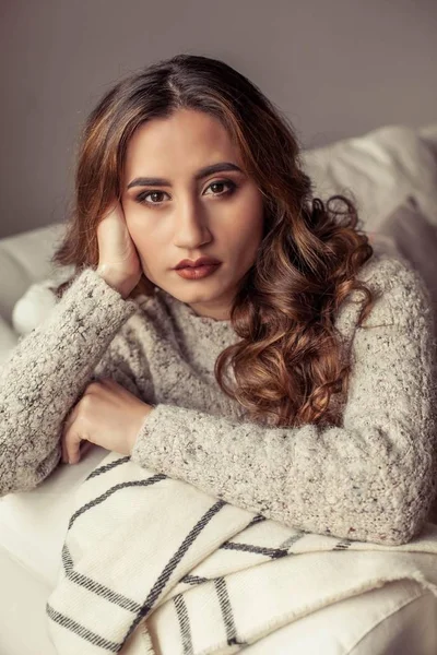 Um retrato aconchegante de uma jovem mulher bonita. Menina turca bonita. Outono quente. Aconchegante noite em casa. Uma jovem se envolveu em um cobertor e se senta no sofá . — Fotografia de Stock