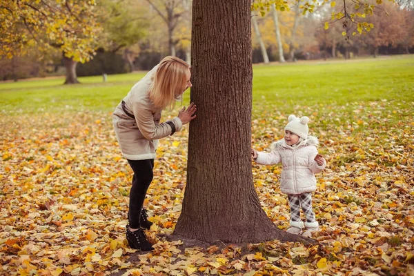 Young mother and little daughter walk in the autumn. Mom and daughter play. Warm winter. Bright autumn. — Stock Photo, Image