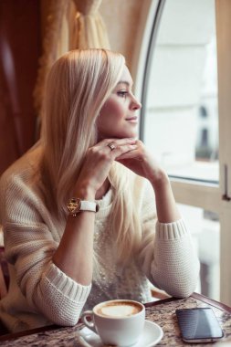 Genç güzel kadın sıcak kakao bir fincan tutuyor. Genç bir kadın rahat bir kafede oturuyor. Kız kakao içiyor. Kış. Rahat sonbahar.