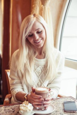 Eller sıcak kakao bir fincan tutun. Genç bir kadın rahat bir kafede oturuyor. Kız kakao içiyor. Kış. Rahat sonbahar.