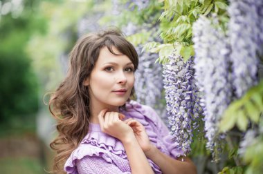 Güzel bir genç esmer kadın portresi. Genç bir kadın Bahar park boyunca yürüyor. Kız wisteria duruyor. Çiçek park. Bahar. Güzellik.