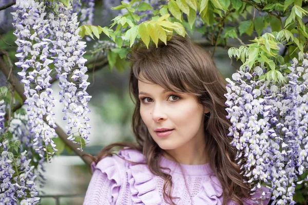 Güzel bir genç esmer kadın portresi. Genç bir kadın Bahar park boyunca yürüyor. Kız wisteria duruyor. Çiçek park. Bahar. Güzellik.