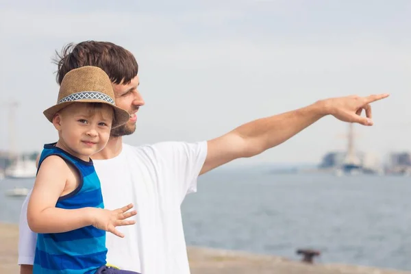 お父さんと息子のビーチで。海。夏。幸せなパパと息子が歩いて、ボートを見て. — ストック写真