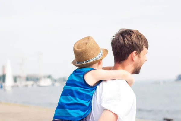 お父さんと息子のビーチで。海。夏。幸せなパパと息子が歩いて、ボートを見て. — ストック写真