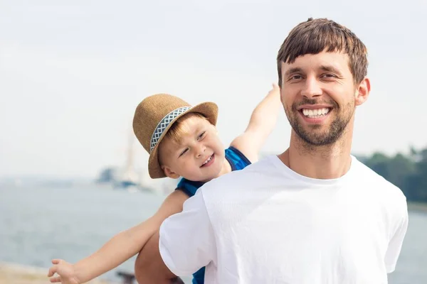 お父さんと息子のビーチで。海。夏。幸せなパパと息子が歩いて、ボートを見て. — ストック写真