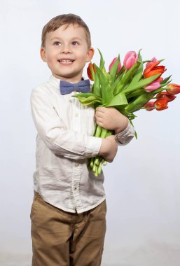 Bir buket çiçek tutan şirin ufaklık. Lale. Anneler günü. Uluslararası Kadınlar Günü. Mutlu bir çocuğun portresi