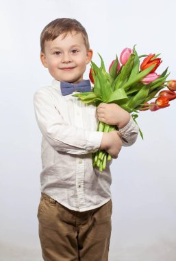 Bir buket çiçek tutan şirin ufaklık. Lale. Anneler günü. Uluslararası Kadınlar Günü. Mutlu bir çocuğun portresi