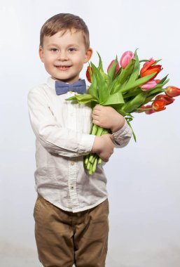 Bir buket çiçek tutan şirin ufaklık. Lale. Anneler günü. Uluslararası Kadınlar Günü. Mutlu bir çocuğun portresi