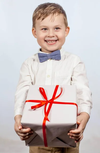 Joli petit garçon avec un cadeau. Joyeux garçon tenant une boîte avec un cadeau. La fête des mères. Journée internationale de la femme. Portrait d'un petit garçon heureux sur fond blanc. Le printemps. Anniversaire . — Photo