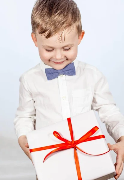 Lindo niño con un regalo. Niño feliz sosteniendo una caja con un regalo. Día de las Madres. Día Internacional de la Mujer. Retrato de un niño feliz sobre un fondo blanco. Primavera. Cumpleaños. . —  Fotos de Stock