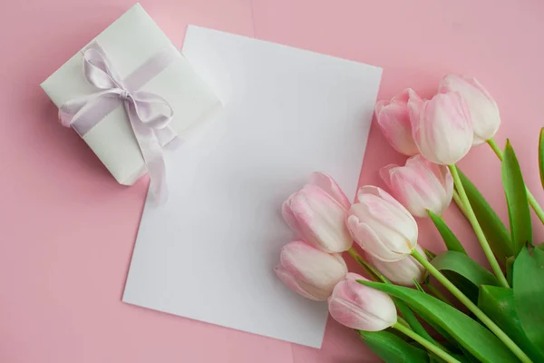 Un ramo de tulipanes, una tarjeta de regalo sobre un fondo rosa. Un regalo. Una caja con un regalo. Día Internacional de la Mujer. Vacaciones. Primavera . — Foto de Stock