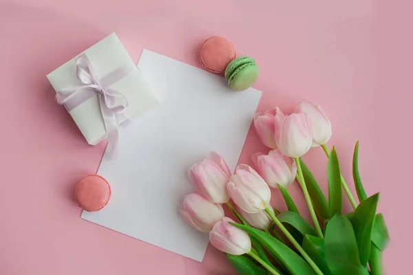 Un ramo de tulipanes, una tarjeta de regalo sobre un fondo rosa. Un regalo. Una caja con un regalo. Día Internacional de la Mujer. Vacaciones. Primavera. Macarrones . — Foto de Stock