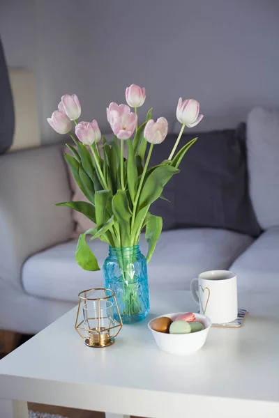 Intérieur. Un bouquet de tulipes dans un vase en verre, du thé chaud, un bougeoir sur une table basse. Une chambre. Confortable. Canapé . — Photo