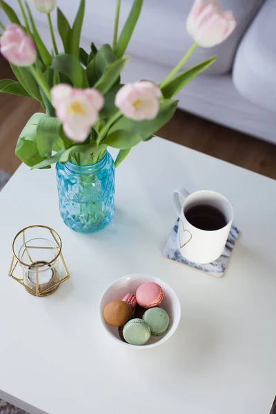 Intérieur. Un bouquet de tulipes dans un vase en verre, du thé chaud, un bougeoir sur une table basse. Une chambre. Confortable. Canapé . — Photo