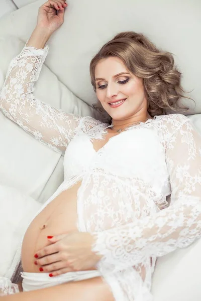 Mladá krásná těhotná žena v pradlo odpočívá doma. Útulný. Portrét mladé šťastné těhotné ženy. Těhotenství. Mateřství. — Stock fotografie
