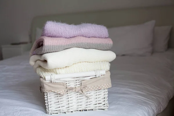 Корзина с чистыми вещами на кровати. Уютно. Трикотажные свитера . — стоковое фото