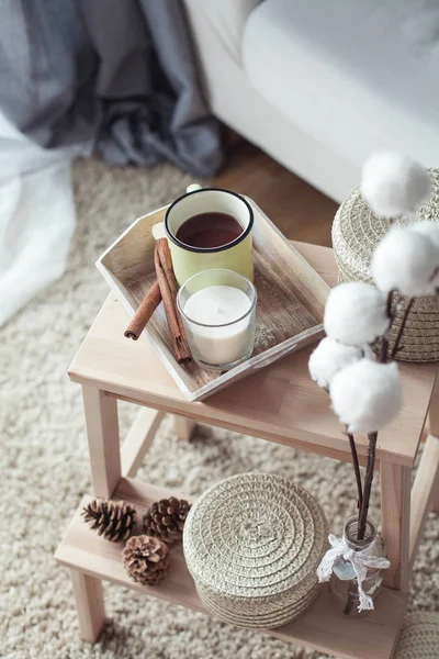 Decoração de casa. Uma mesa de cabeceira de madeira, um sofá, um algodão, uma caneca de café quente, uma xadrez de malha. Casa quente. Outono. Aconchegante. Casa. O livro e os óculos. Interior . — Fotografia de Stock