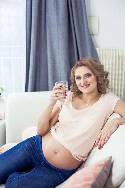 아름 다운 임신한 여자는 물 한 잔을 들고 있다. 건강입니다. 임신입니다. 어머니입니다. 젊은 임산부 음료 물. — 스톡 사진