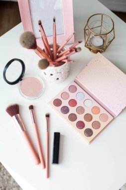 Kozmetik. Makyaj. Tuvalet Masası. Ev dekorasyonu. Mum, göz farı, makyaj fırçaları, ruj, toz. Parlaklık. Pembe altın. Makyaj araçları. Rahat.