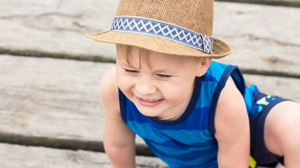 Roztomilý malý chlapec sedí na molu. Šťastný chlapec na pláži. V létě. Rekreace. Cestovní ruch. Moře. — Stock fotografie