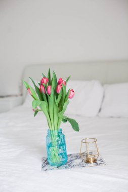 Ev iç. Yatak odası. Bir buket Lale bir cam vazo, bir mum, bir tepsi, bir kutu bir hediye ile yatağa hazır. Sabah. Bahar. Yaz. Tatil. Uluslararası Kadınlar Günü. Anneler günü.