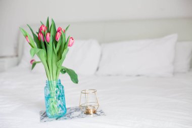 Ev iç. Yatak odası. Bir buket Lale bir cam vazo, bir mum, bir tepsi, bir kutu bir hediye ile yatağa hazır. Sabah. Bahar. Yaz. Tatil. Uluslararası Kadınlar Günü. Anneler günü.