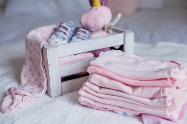 Çocuk ayakkabı ve giysileri yatağın üstünde. Güzel pembe bebek giysileri. Yeni doğan. Ev rahatlık. Bebek.