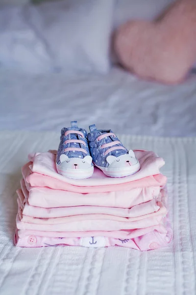 Sapatos infantis e roupas na cama. Roupas cor-de-rosa bonitas. Recém-nascido. Conforto em casa. Querida... . — Fotografia de Stock