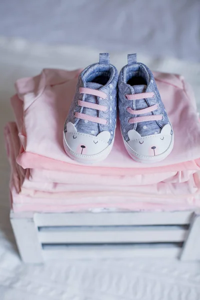 Children's shoes and clothes on the bed. Beautiful pink baby clothes. Newborn. Home cosiness. Baby. — Stock Photo, Image