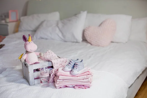 Kinder schoenen en kleding op het bed. Mooie roze babykleding. Pasgeborene. De gezelligheid van het huis. Baby. — Stockfoto