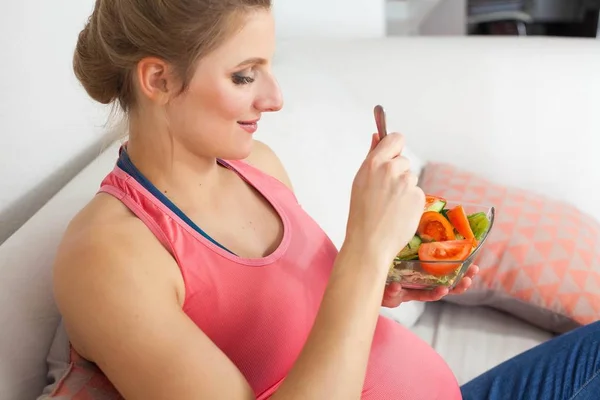 젊은 아름 다운 임신한 여자는 야채 샐러드를 먹고 있다. 소녀는 샐러드 접시를 들고 있다. 건강 한 먹는입니다. 임신입니다. 어머니입니다. 건강. — 스톡 사진