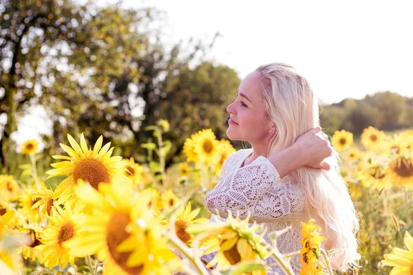 Schöne junge Frau in einem Sonnenblumenfeld. Porträt einer schönen Blondine. Ein Mädchen ruht sich im Park aus. Sommer. Hitze. — Stockfoto