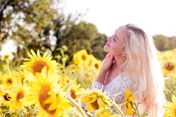 Schöne junge Frau in einem Sonnenblumenfeld. Porträt einer schönen Blondine. Ein Mädchen ruht sich im Park aus. Sommer. Hitze. — Stockfoto