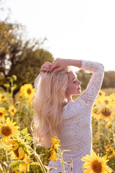 Schöne junge Frau in einem Sonnenblumenfeld. Porträt einer schönen Blondine. Ein Mädchen ruht sich im Park aus. Sommer. Hitze. — Stockfoto
