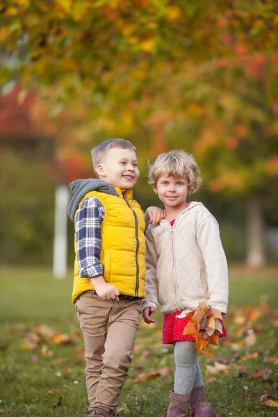 男の子は女の子を抱きしめる。明るい秋の服で幸せな子供の肖像画。暖かく明るい秋. — ストック写真