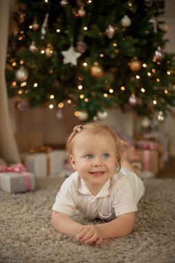 İki yıllık pijamalı küçük tatlı kız Noel ağacında hediyeler açıyor. Noel zamanı. Yeni yıl. Tatillerde. Samimi.