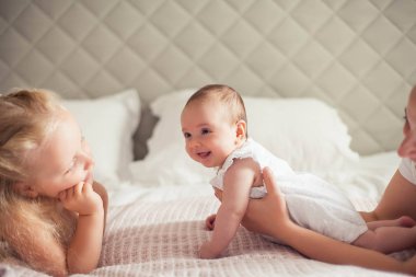 Genç ve güzel bir anne bir bebek doğuruyor. Küçük kız kardeşi küçük kız kardeşini öper. Bebek. Çocuk yatak odası.