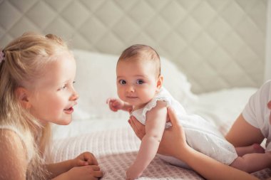 Genç ve güzel bir anne bir bebek doğuruyor. Küçük kız kardeşi küçük kız kardeşini öper. Bebek. Çocuk yatak odası.