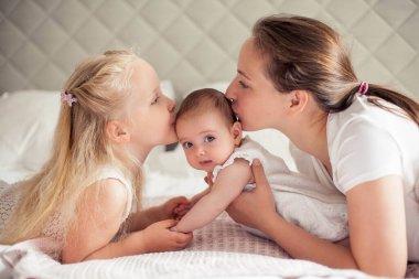 Genç ve güzel bir anne bir bebek doğuruyor. Küçük kız kardeşi küçük kız kardeşini öper. Bebek. Çocuk yatak odası.