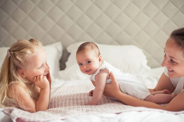 Joven hermosa madre sostiene a un bebé. La hermanita besa a su hermanita. Nena. Dormitorio para niños . — Foto de Stock